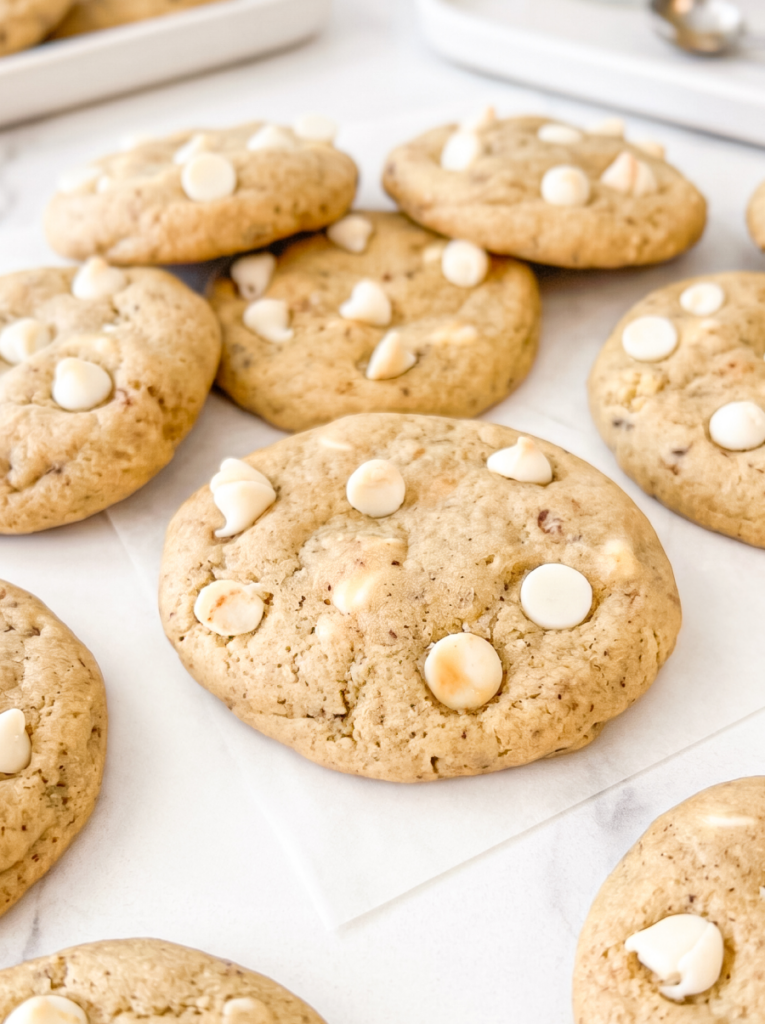 Soft coffee-speckled cookies topped with white chocolate chips arranged on white parchment paper, photographed from above at a slight angle.
