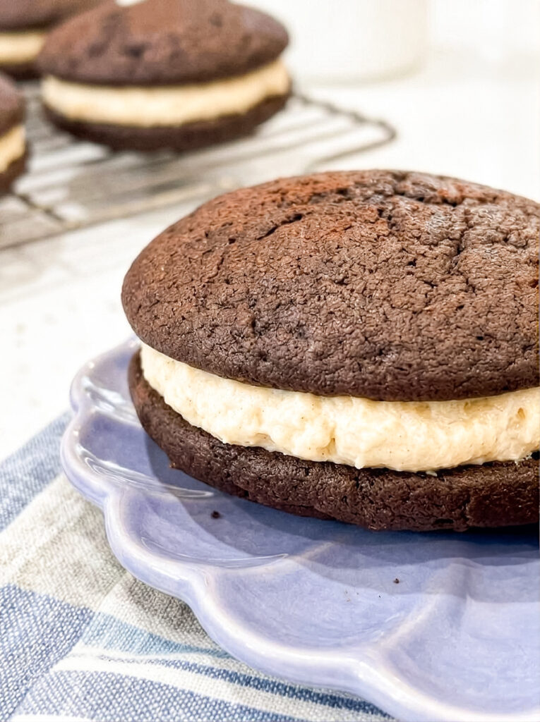 Tiramisu whoopie pie with chocolate cake and cream filling on a purple plate.