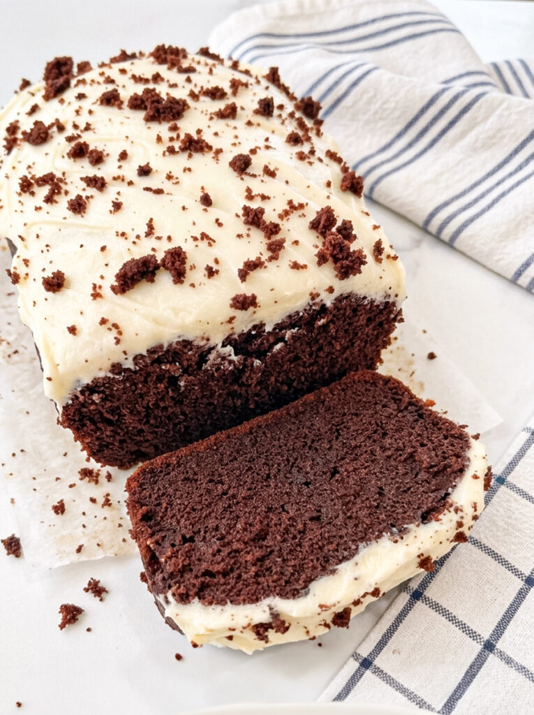 Sliced red velvet loaf cake with cream cheese frosting on a white plate