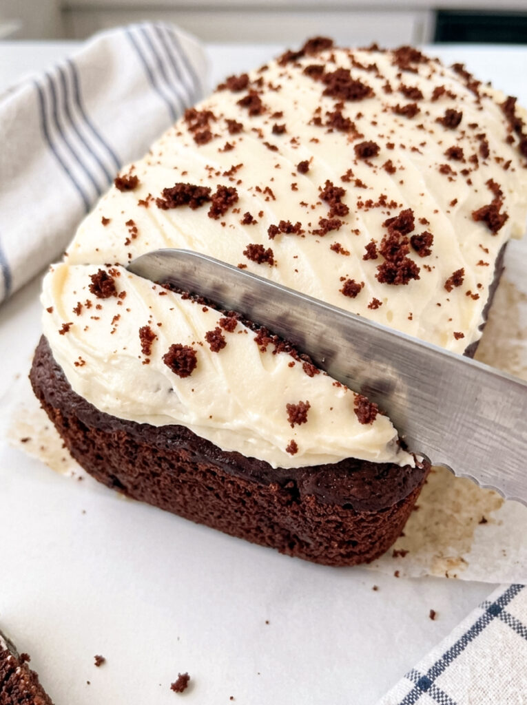 Sliced red velvet loaf cake with cream cheese frosting on a white plate