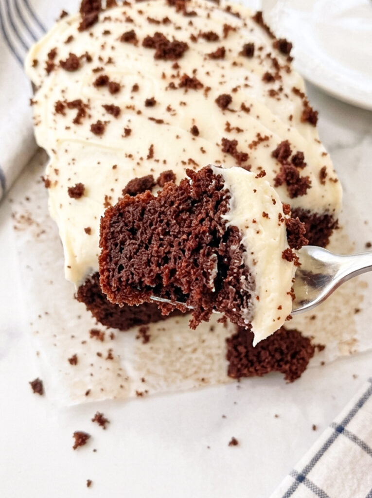 Sliced red velvet loaf cake with cream cheese frosting on a white plate