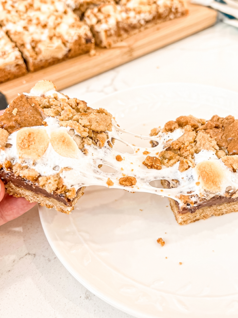 A hand pulls apart a biscoff s'mores bar, revealing gooey stretched marshmallow