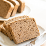 Three slices of hojicha castella cake with a delicate brown crumb are stacked on a white plate with a fork, with more slices in the background.