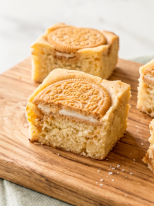 Golden Oreo blondies on a wooden board, with a visible cream-filled cookie half embedded in each square.