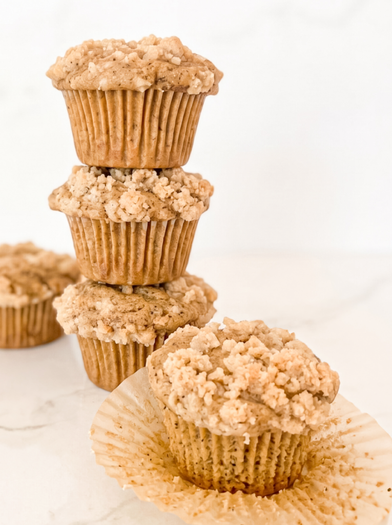 Three Earl Grey crumble muffins with a fourth muffin partially unwrapped in the foreground.