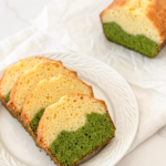 Four slices of a matcha latte pound cake with green bottom and light yellow top layers are arranged on a white plate, with the rest of the loaf in the background.