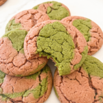 A pile of pink and green marbled cookies, one with a bite taken out, showing its textured surface.