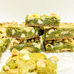 I hold up a square matcha bar with white chocolate chips, melted marshmallow, and graham cracker pieces, with more bars in the background.