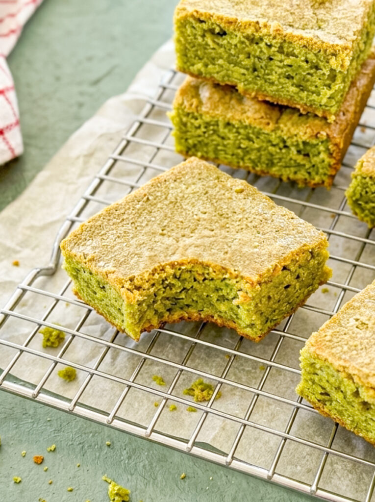 Matcha blondies with a bite taken out on a cooling rack.