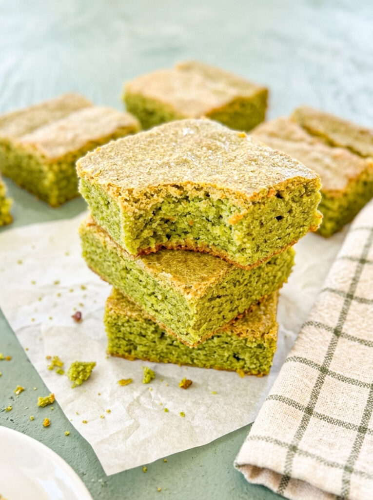 Matcha blondies stacked on parchment paper.