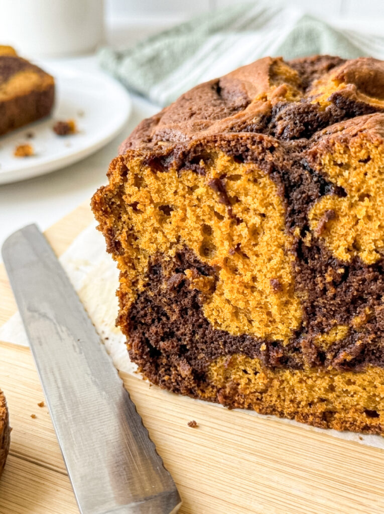 Pumpkin Nutella swirl loaf with a chocolate marbling pattern on a wooden cutting board.