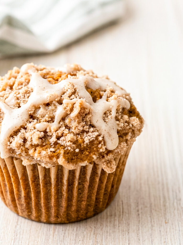 Pumpkin streusel muffin topped with crumble topping and white icing drizzle.